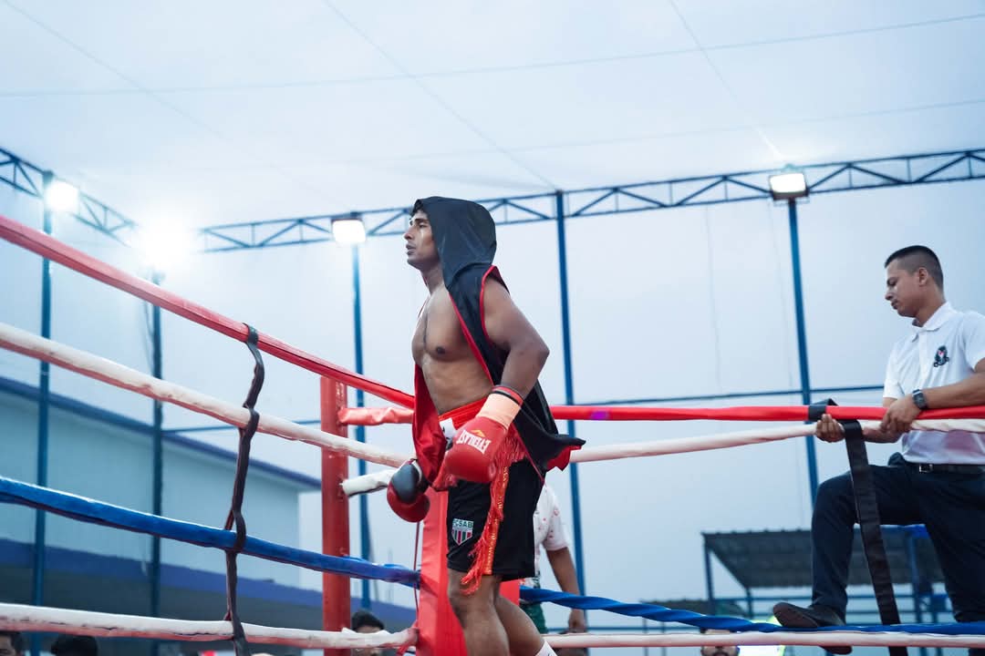 A boxer in red shorts in the corner of a floodlit ring