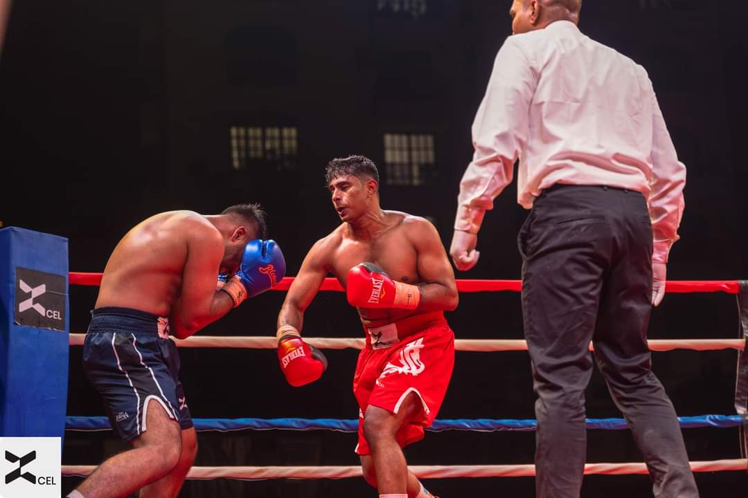 A boxer in red shorts on the attack as the referee watches