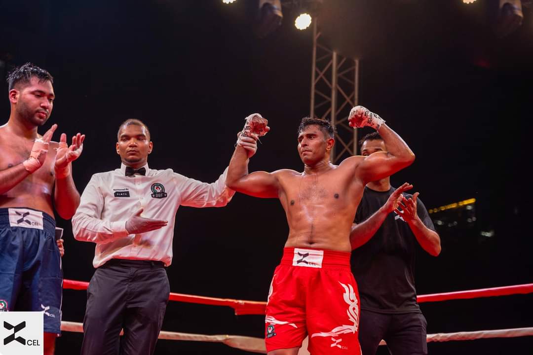 The referee raises the hand of a boxer in red shorts