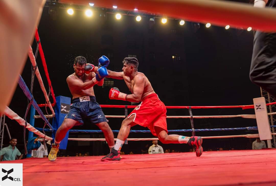 A boxer in red shorts throwing a punch, wide shot of the ring