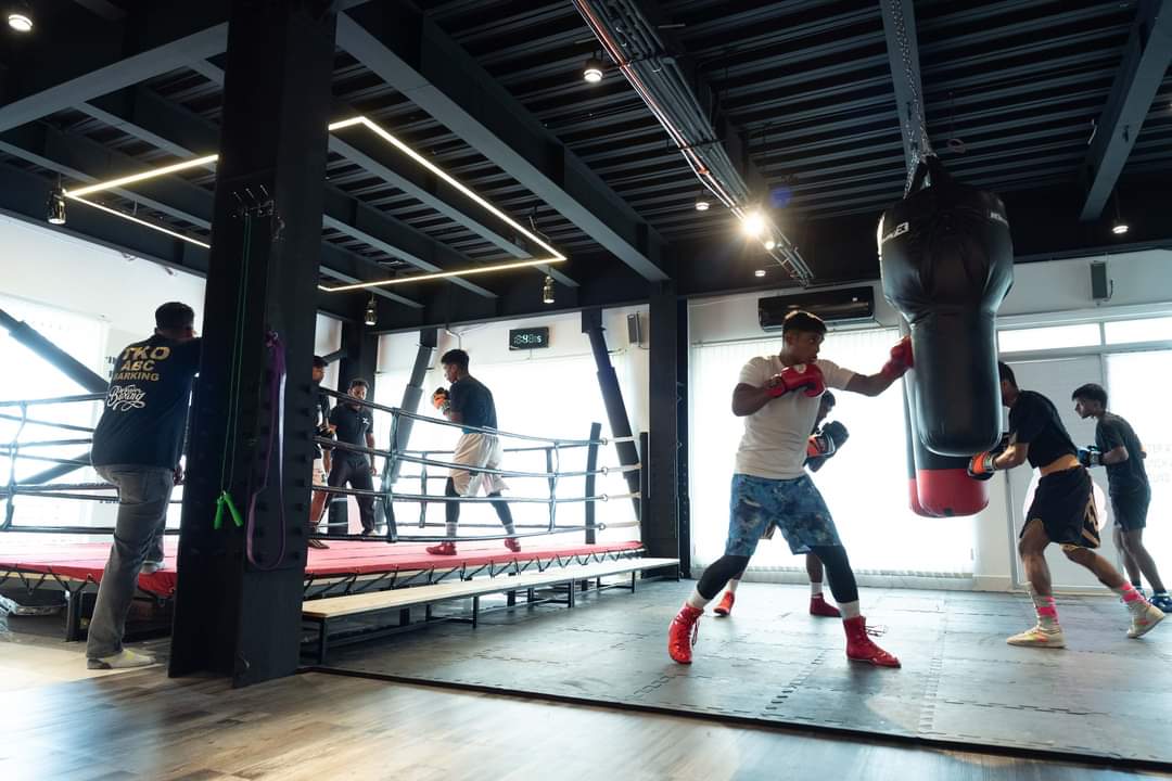 A training session in a gym, heavy bags and ring