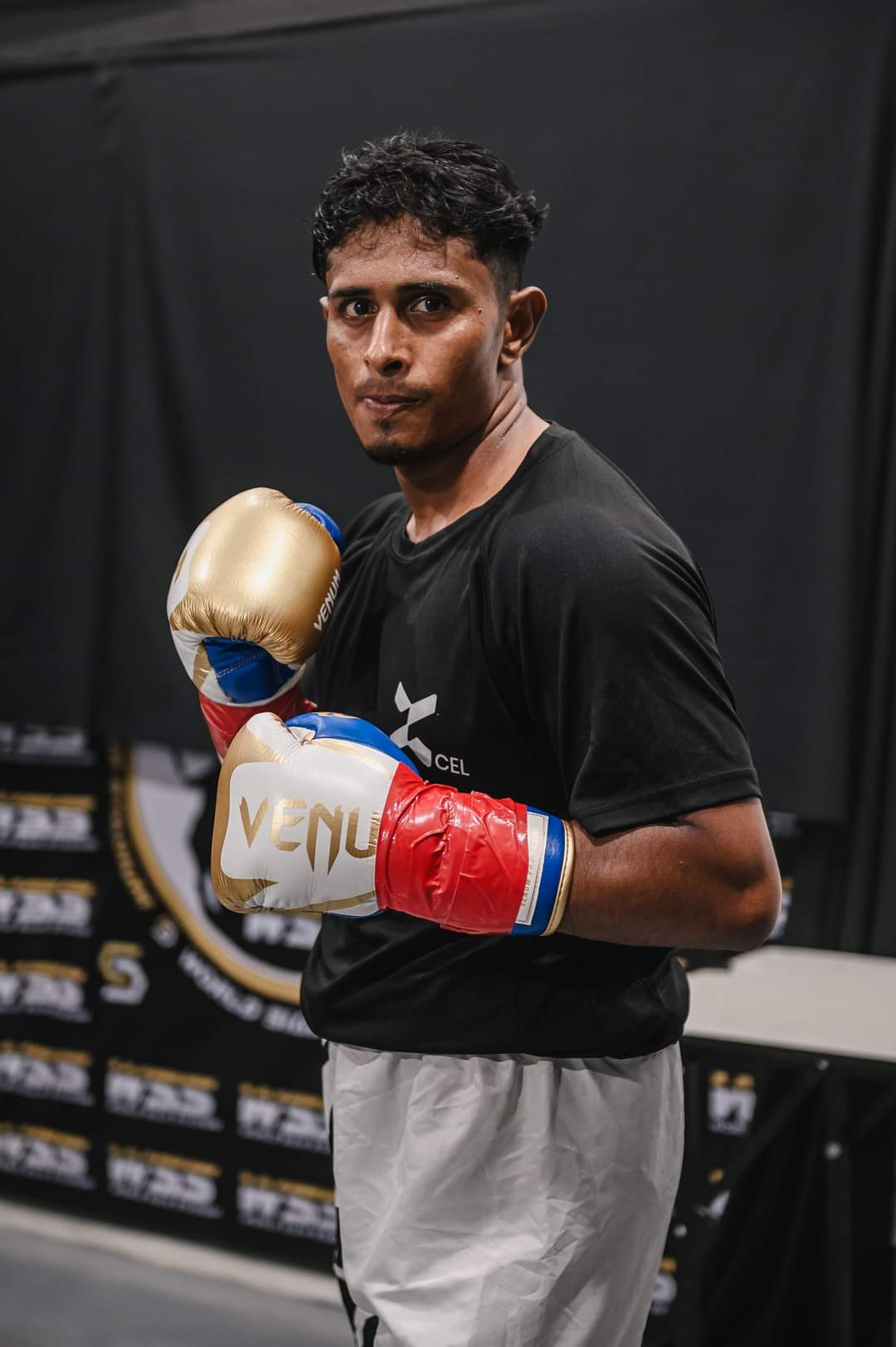 Al-Amin in a black T-shirt and gold gloves
