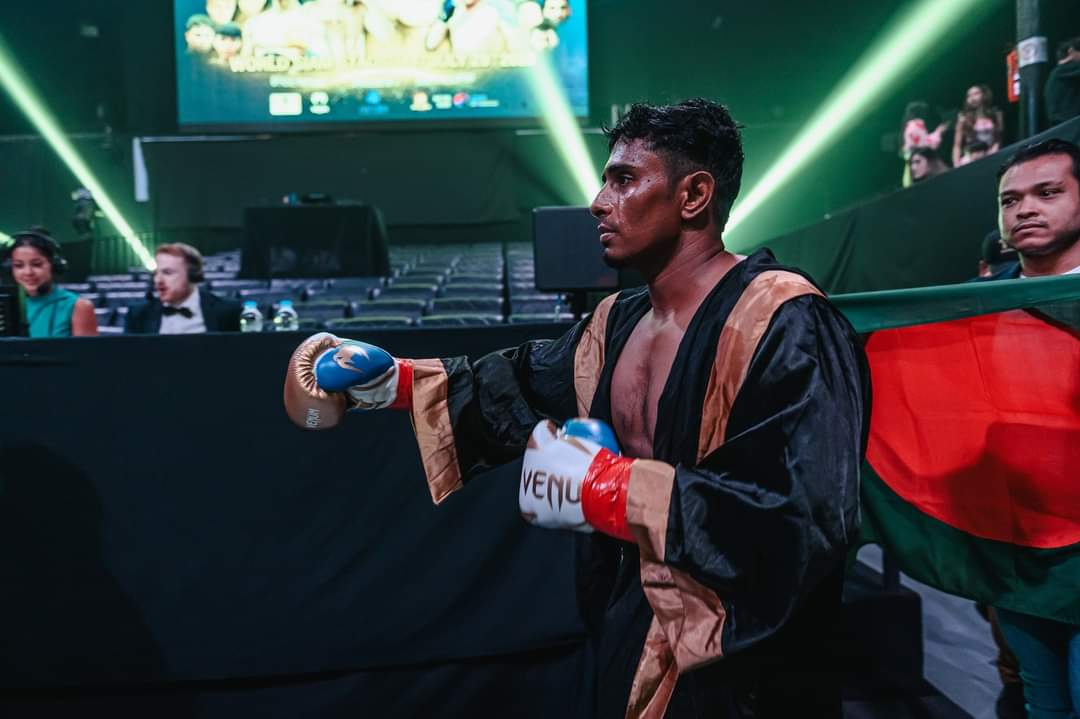 Al-Amin in his robe on the ring walk, the Bangladesh flag behind him