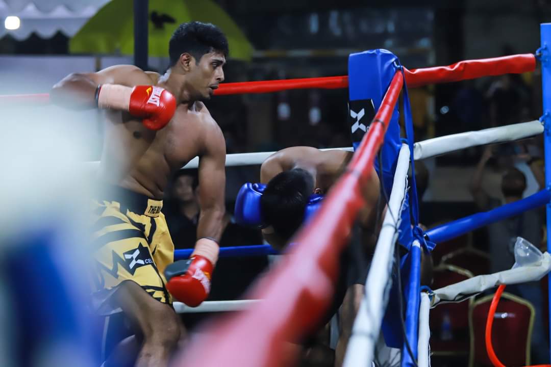 A boxer in yellow and black shorts on the ropes, close up