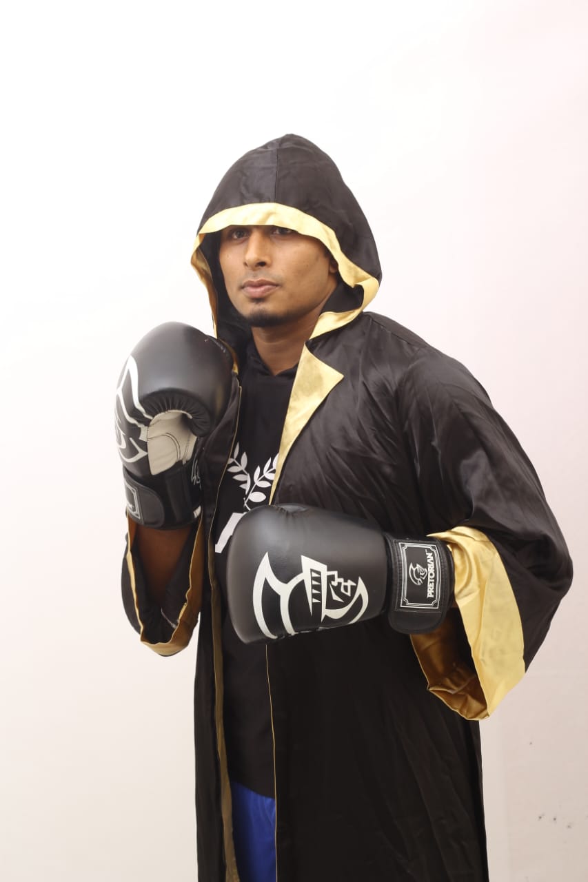 Studio portrait: Al-Amin in a hooded black and gold robe