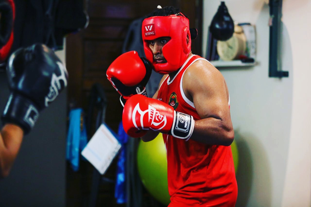 Al-Amin sparring in red headgear and a red vest