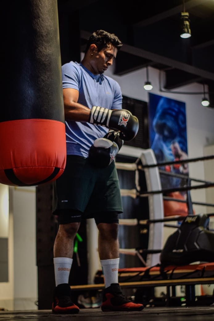 Al-Amin pulling on his gloves by the heavy bag