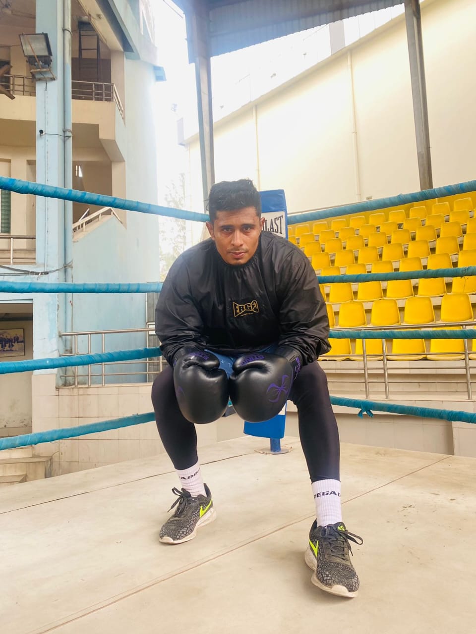 Al-Amin crouched at the edge of a ring in an empty arena