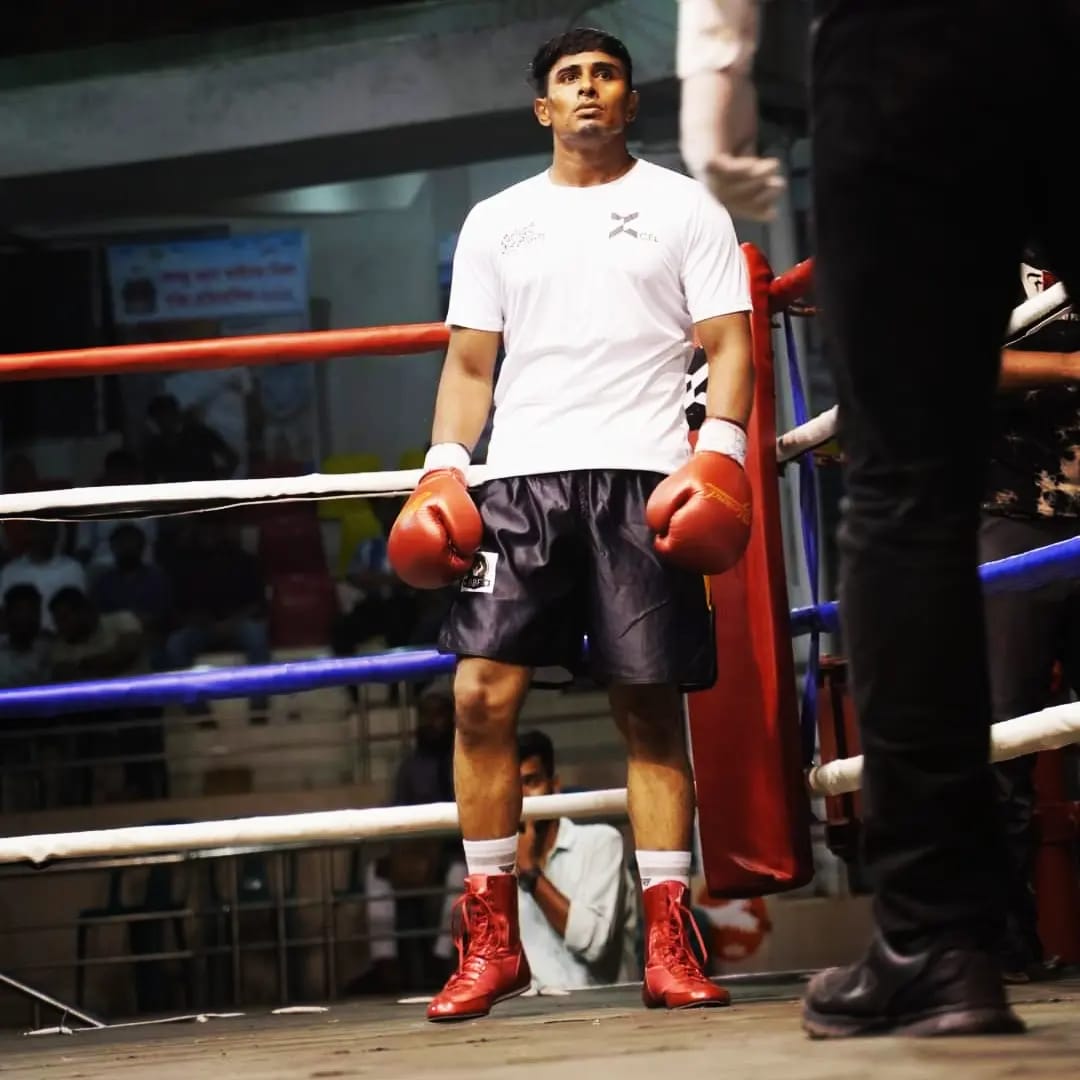 Al-Amin in a white T-shirt and gloves standing in the ring