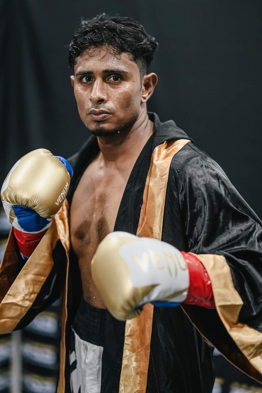 Al-Amin in his black and gold ring robe, gloves raised
